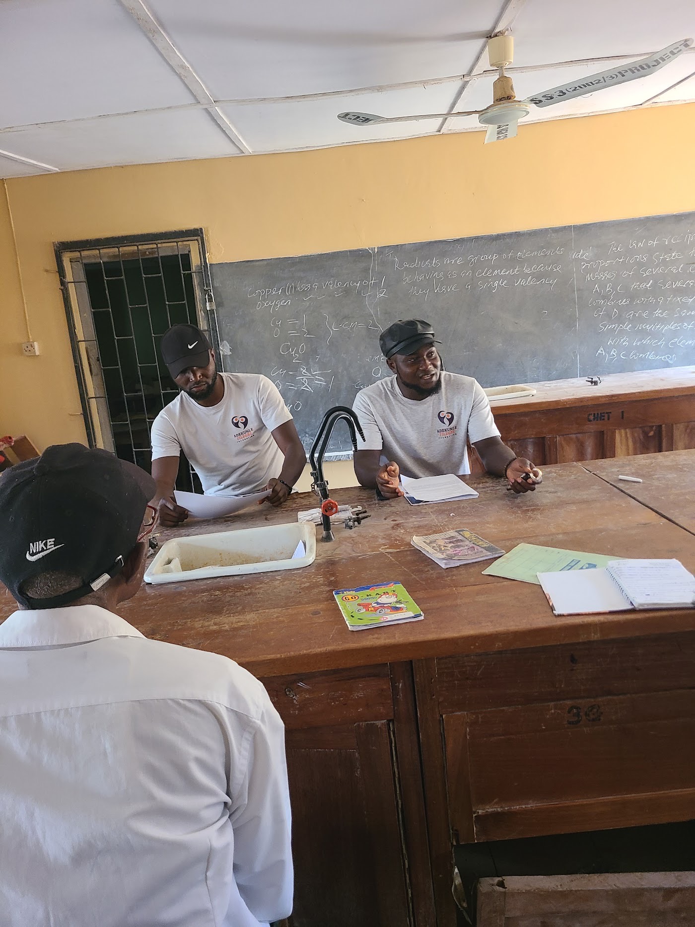 Foundation volunteers talking with a teacher in a science room.