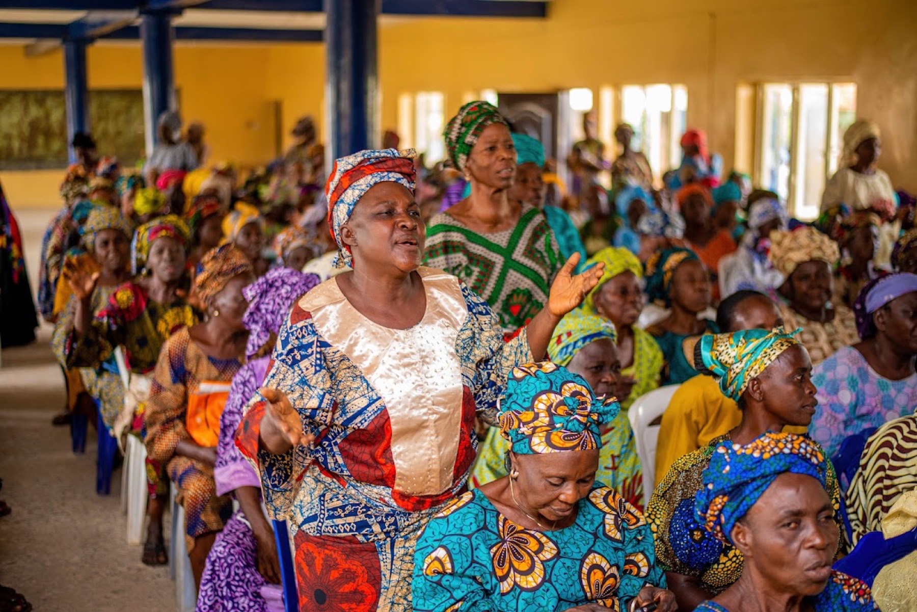 A woman standing to speak in a hall of women.